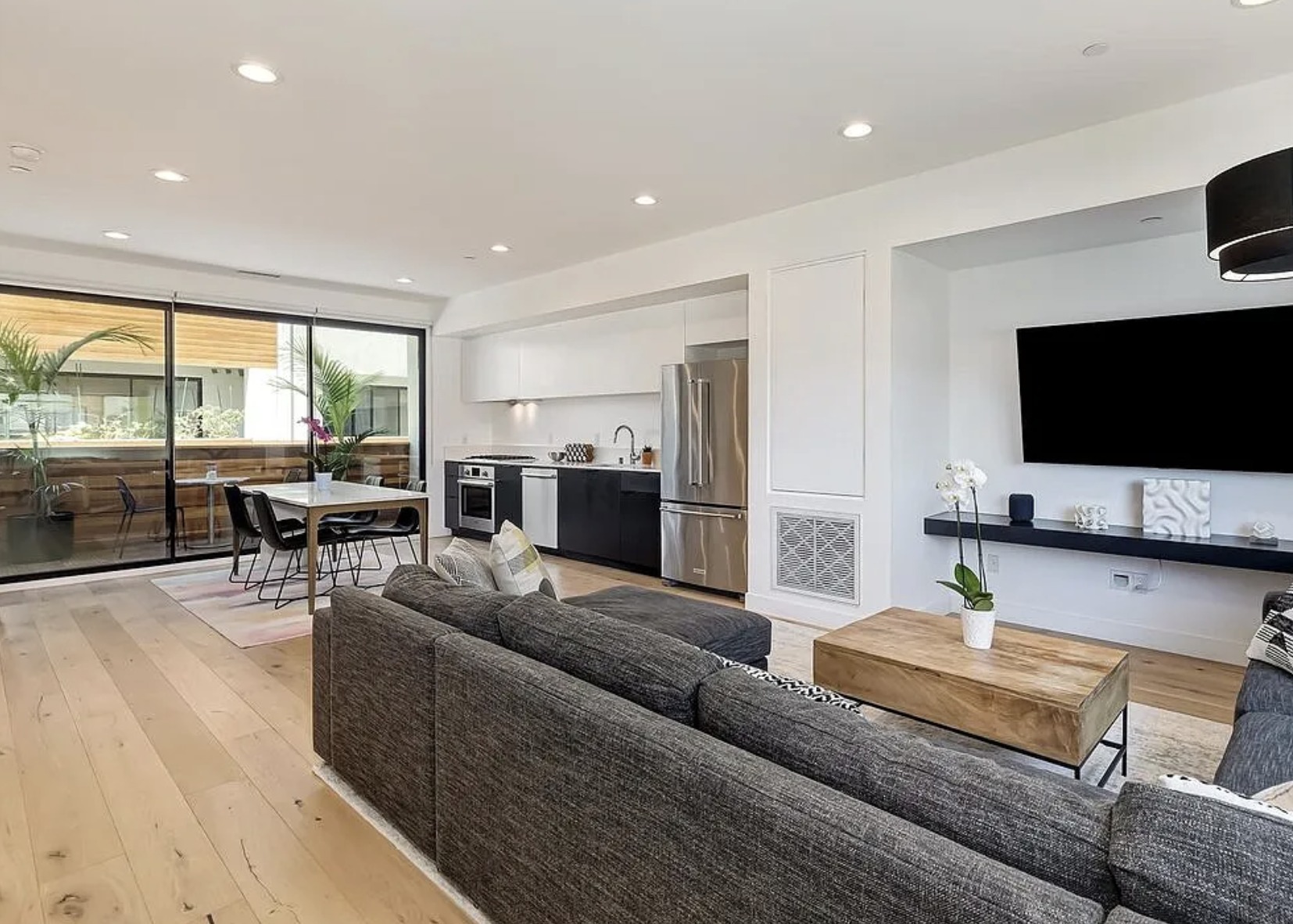 Open-plan kitchen and living room with engineered white oak floors and sliding glass walls to a private deck